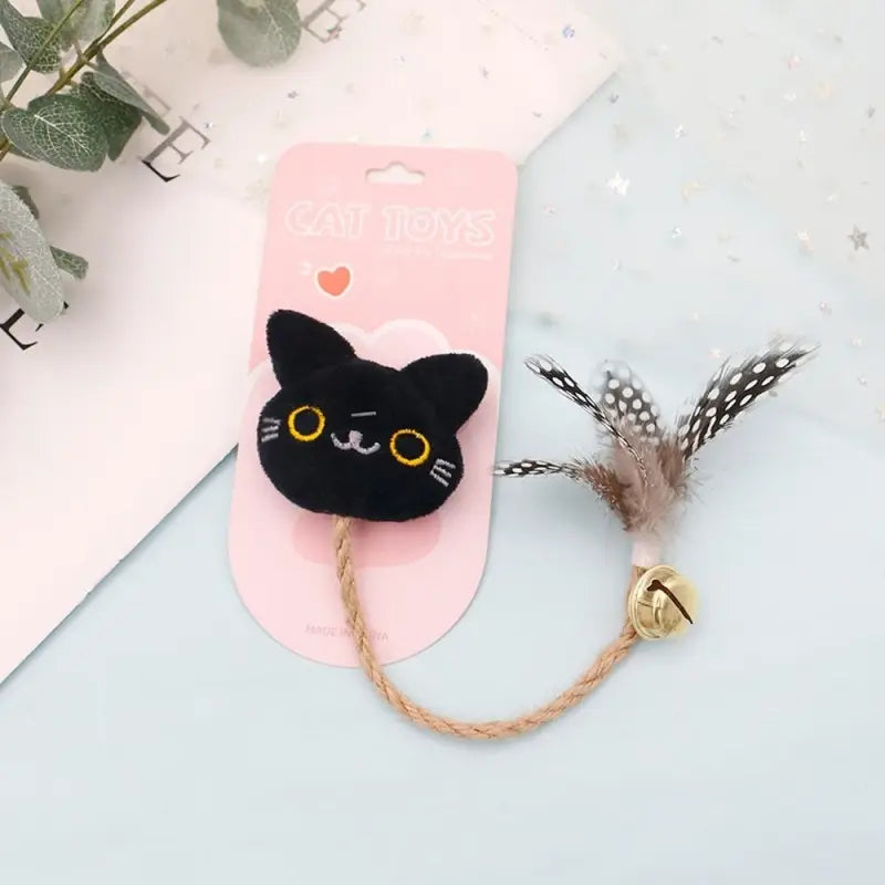 Chat noir aux yeux jaunes et à la médaille rose jouant avec un jouet à mâcher pour chats, plume et menthe