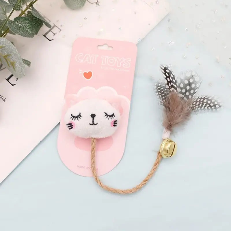 Photo d’un chat rose et blanc avec une plume sur le nez, adorant son ’jouet à mâcher pour chats’